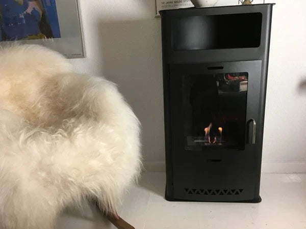 Boston black bioethanol stove lit in a cozy living room with a sheepskin throw and framed art