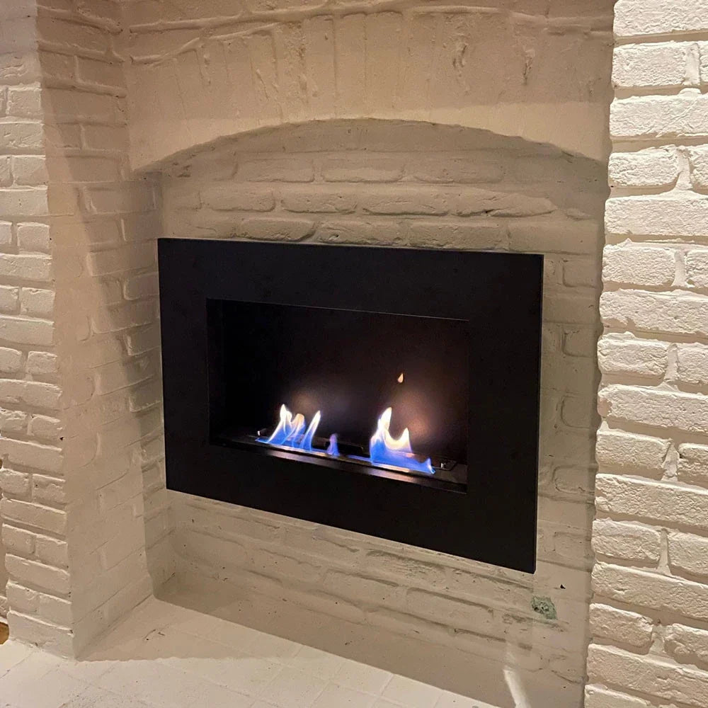 Murus 800 black bio fireplace built into a whitewashed brick alcove, lit flame